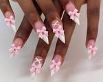 Close-up picture of a person's nails with pink bows and a white lace-up design